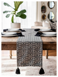 Black and white tasseled table runner styled on a dining table in a monochrome setting