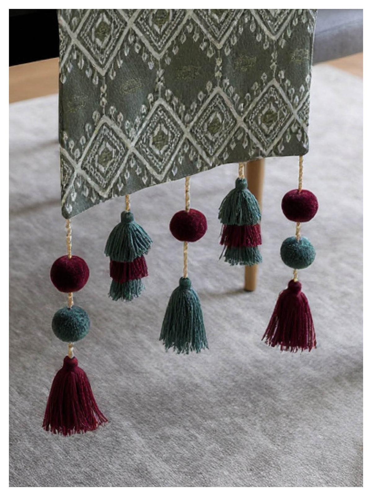 Decorative table runner with tassels on a gray surface