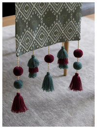 Decorative table runner with tassels on a gray surface