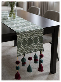 Grey Table runner with geometric pattern and tassels on a dining table