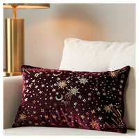 Crimson starburst lumbar pillow with gold, rose gold and champagne metallic embroidery styled on a couch