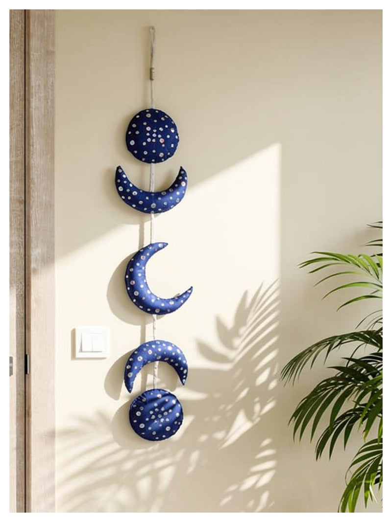 Decorative wall hanging with blue moon phases on a neutral wall.