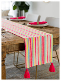 Colorful striped table runner with tassels on a wooden table.