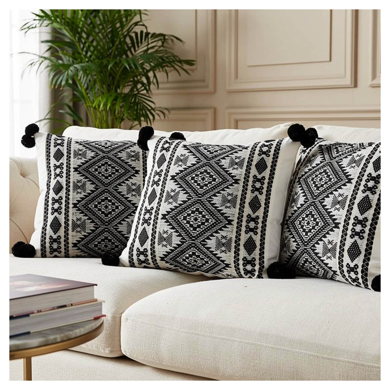 Decorative pillows with black and white patterns on a white sofa in a living room setting.
