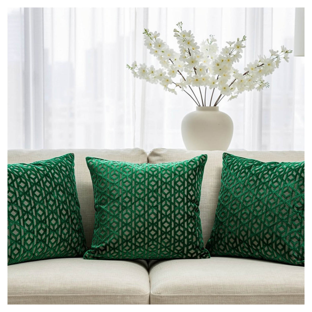 Emerald green velvet cushion set styled on a sofa in a layered arrangement