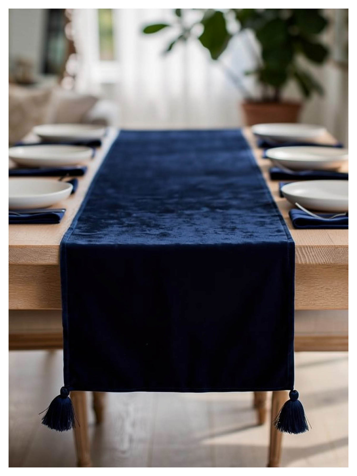 Navy blue table runner with tassels on a wooden dining table.