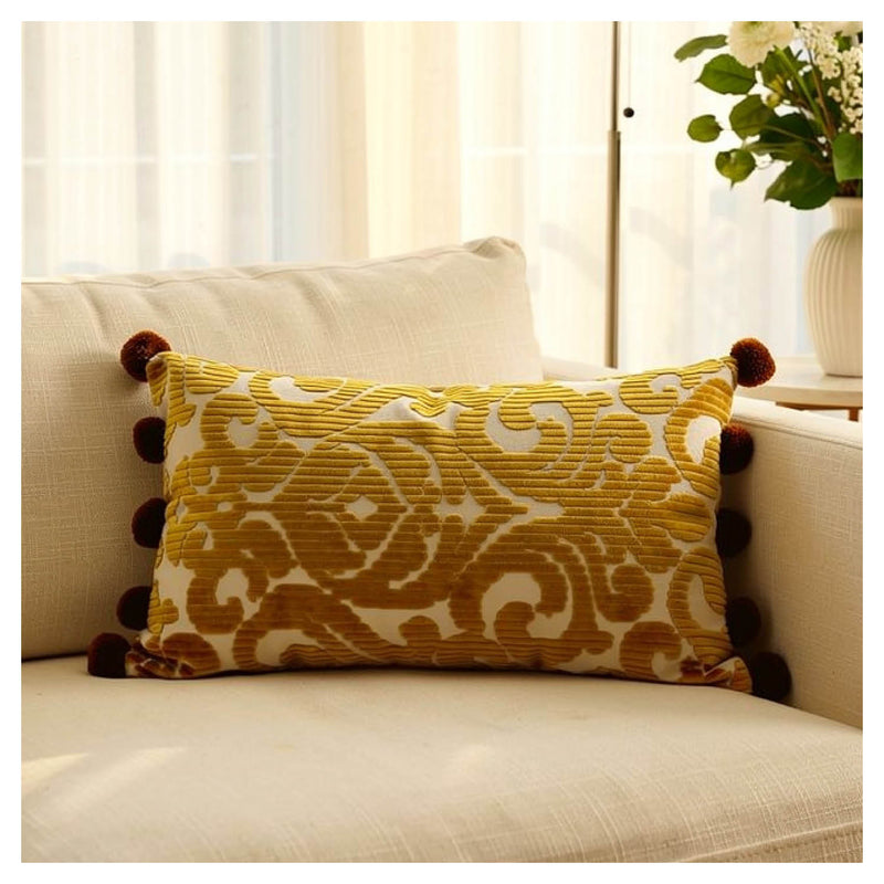 Golden mustard velvet jacquard lumbar pillow with pom-pom edging styled on a beige sofa