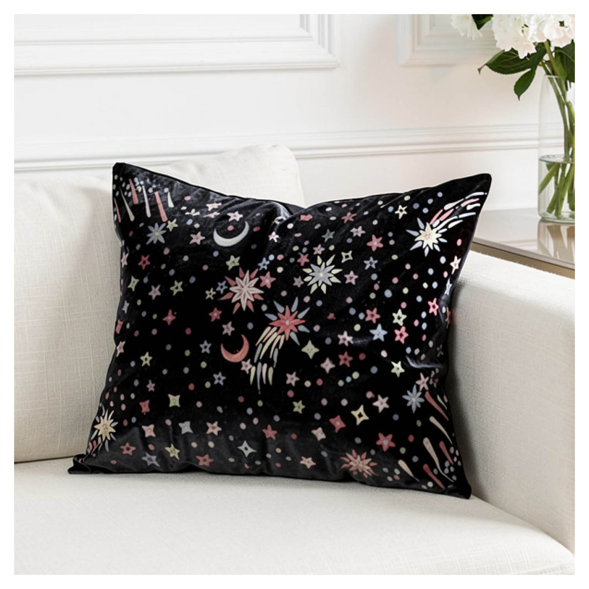 Black starburst square cushion with gold, rose gold and champagne metallic embroidery styled on a white couch